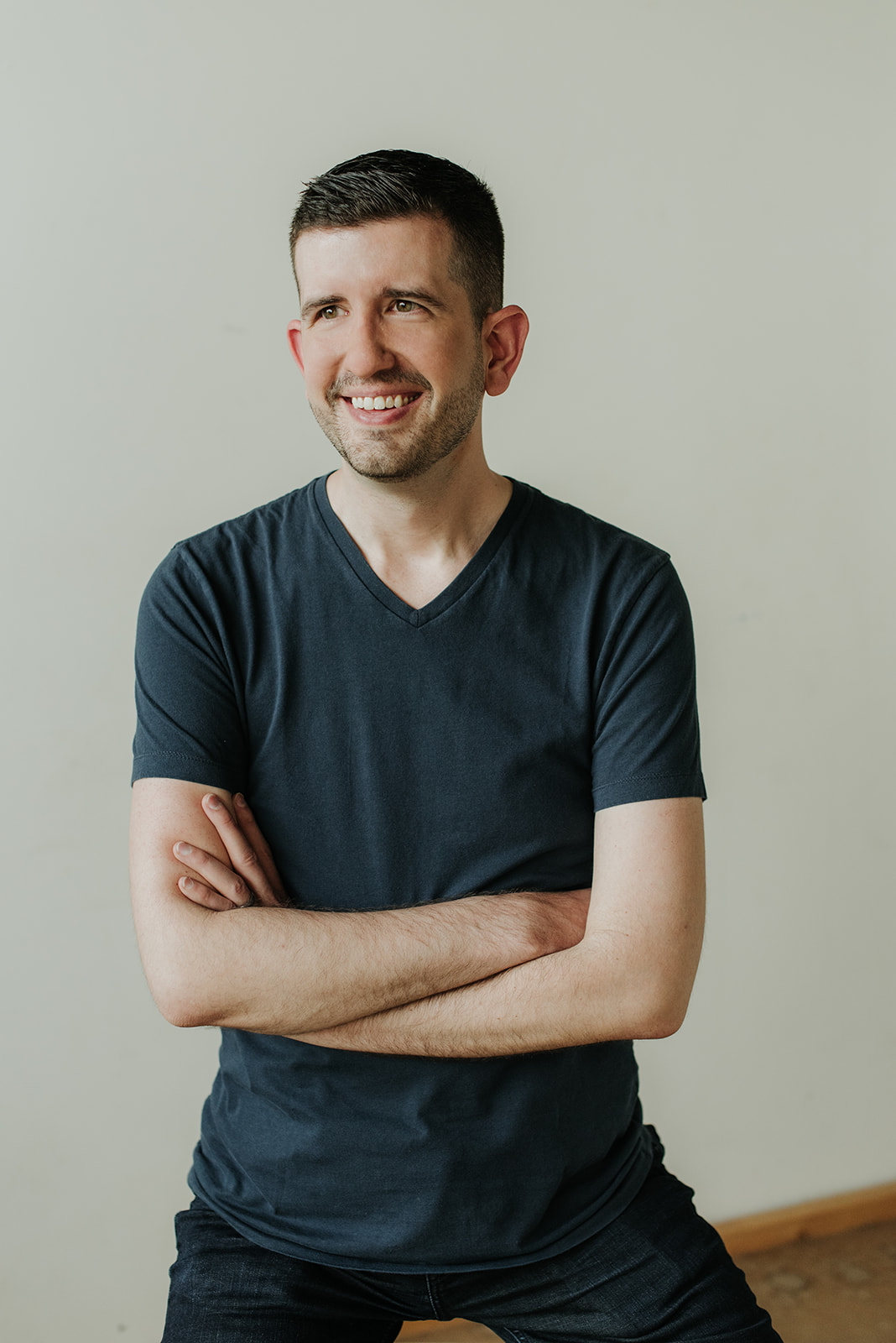 Phil Stamper, smiling with arms crossed, wearing a navy t-shirt